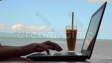 年轻白种人女士使用笔记本电脑和饮用芒果水果奶昔与海景的循环电影。 远程工作和